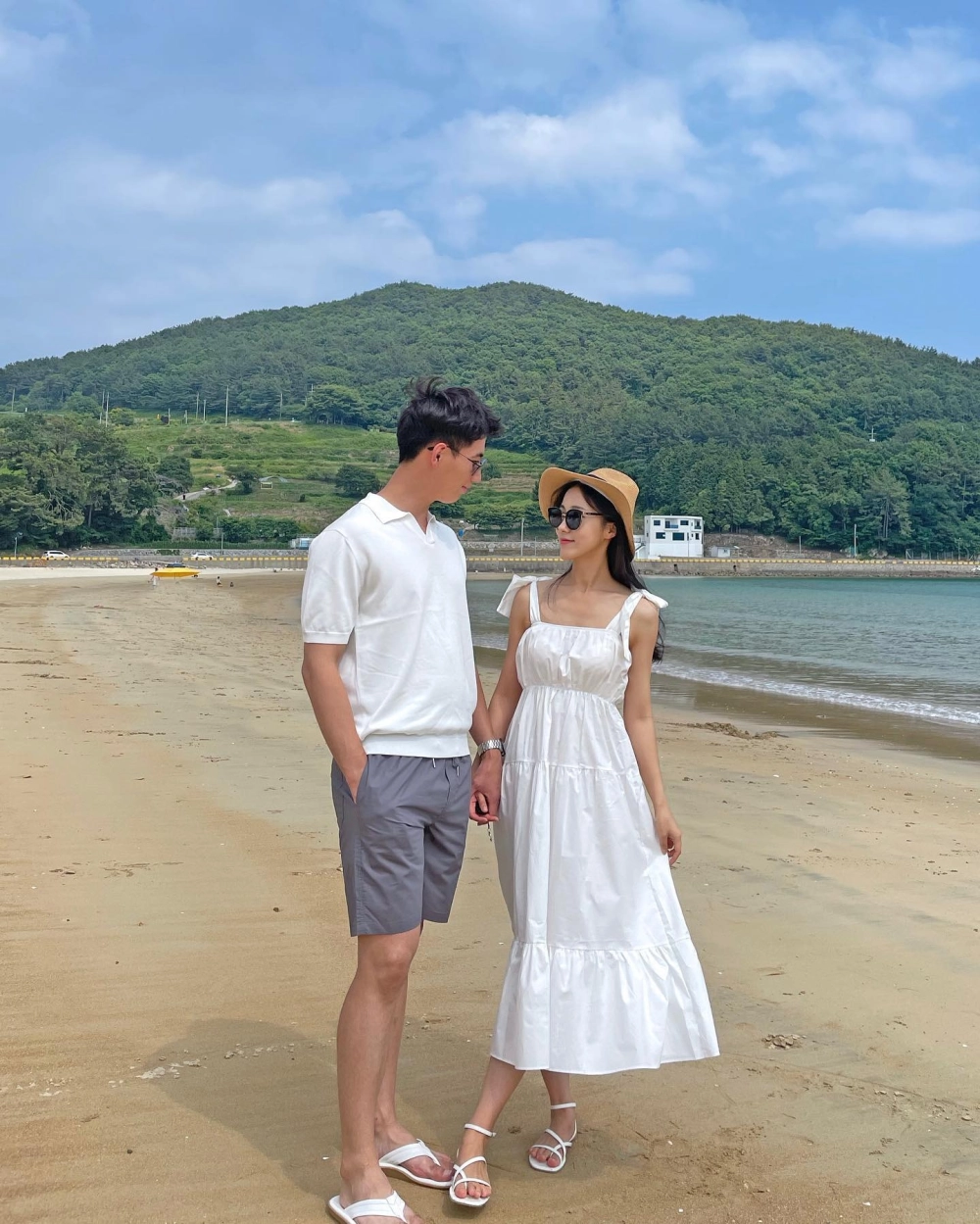 Cặp đôi mặc váy maxi và áo sơ mi cùng tông màu xanh dạo chơi trên bãi cát