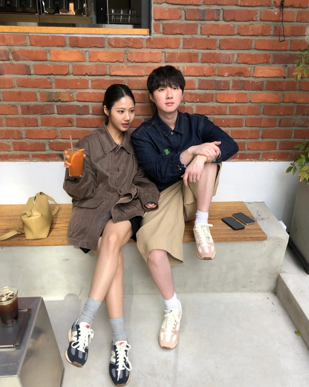 Hai bạn trẻ diện giày đôi phong cách cổ điển ngồi thư giãn bên bức tường gạch