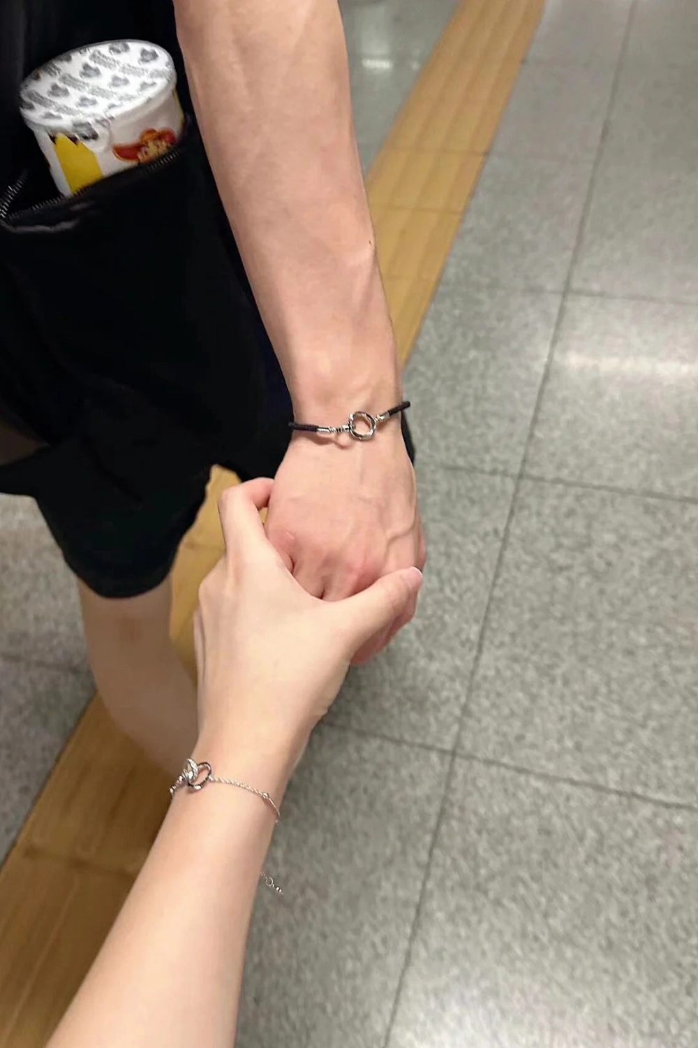 Cặp đôi nắm tay khoe vòng tay đôi bạc thiết kế mắt xích tròn tối giản
