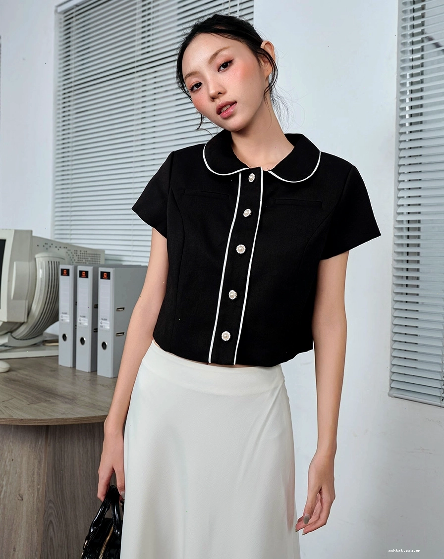 Áo dài cổ lá sen trắng đính nút hoa, phối cùng quần lụa trắng ống rộng và túi xách mini