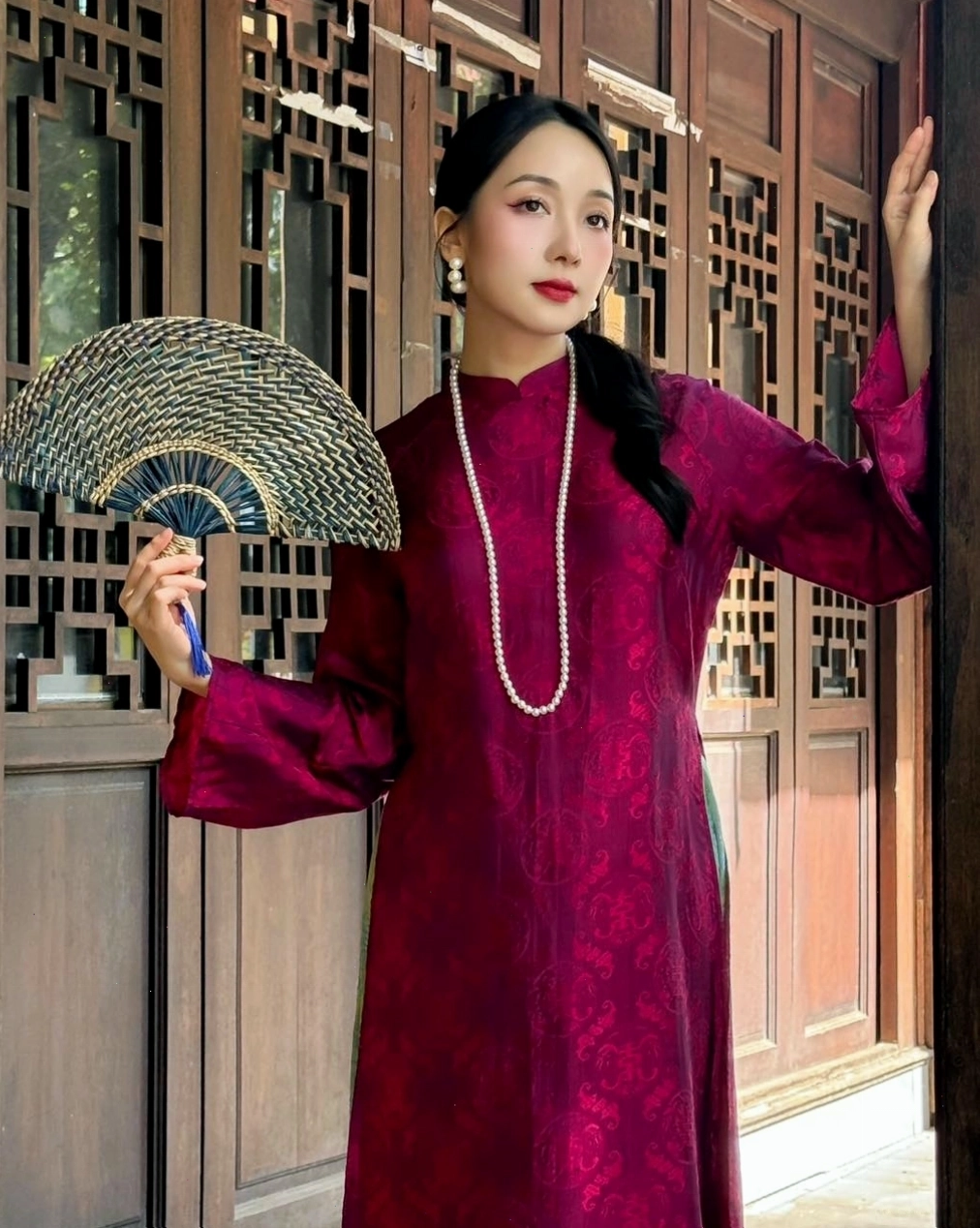 Áo dài cổ tròn màu đỏ, tay lỡ, họa tiết hoa, phối cùng vòng cổ ngọc trai