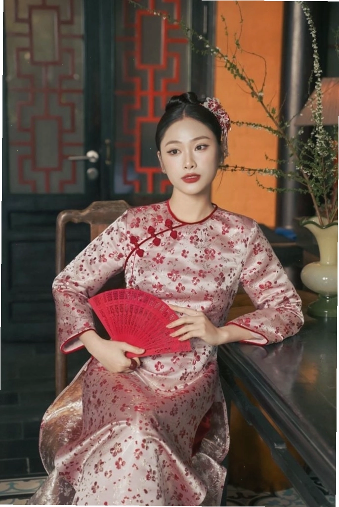Áo dài gấm hoa đỏ với cổ tròn và tay lỡ, mang vẻ đẹp cổ điển nhưng không kém phần hiện đại.