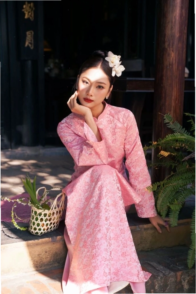Áo dài gấm màu xanh cổ vịt, cổ tròn, tay lỡ, mang vẻ đẹp thanh lịch và quý phái.