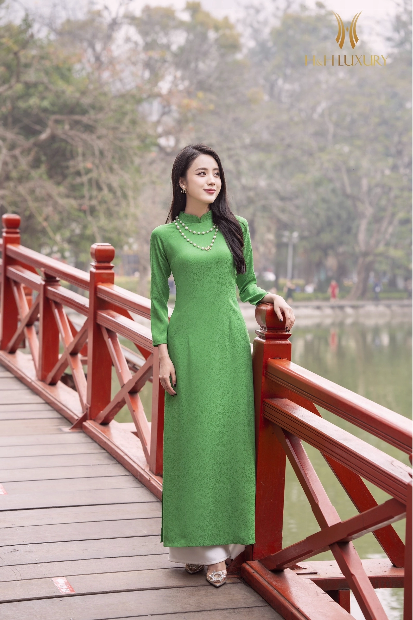 Áo dài lụa gấm hoa cúc xanh thanh thoát, tay áo bồng bềnh nhẹ nhàng.