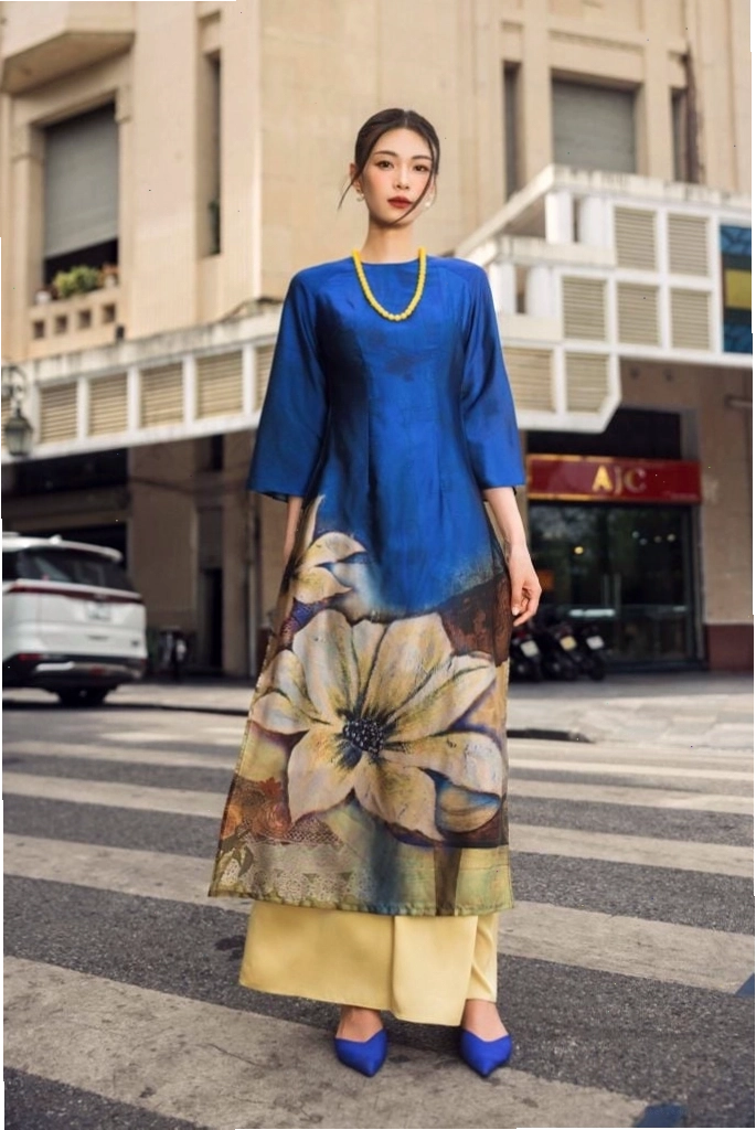 Áo dài lụa in hoa, cổ tròn, tay lỡ, gam màu hồng phấn, họa tiết hoa nhí, mang vẻ đẹp ngọt ngào, nữ tính.