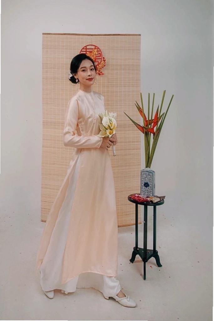 Áo dài lụa tơ tằm màu cam pastel dáng cách tân, cổ tròn, tay lỡ, phối cùng chân váy midi lụa