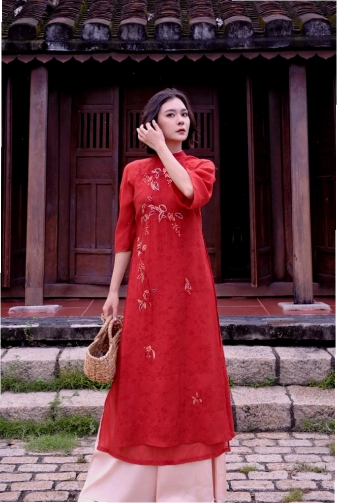 Áo dài thiết kế cổ tròn tay ngắn, chất liệu gấm, màu vàng đồng, họa tiết hoa văn to, mang vẻ đẹp sang trọng, quyền quý.