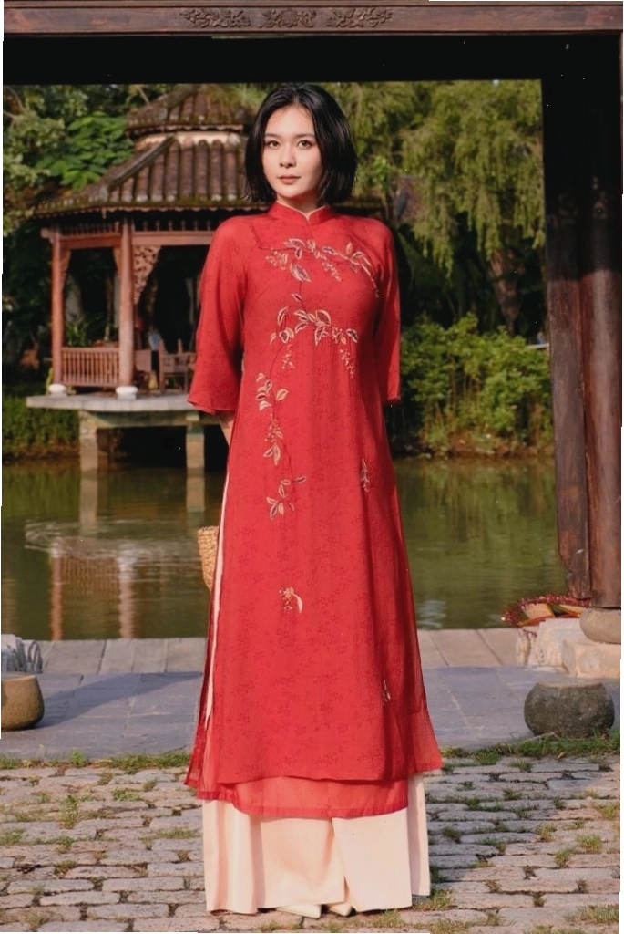Áo dài thiết kế cổ tròn tay ngắn, chất liệu lụa bóng, màu xanh ngọc bích, họa tiết hoa văn nhỏ, mang vẻ đẹp thanh lịch, trẻ trung.