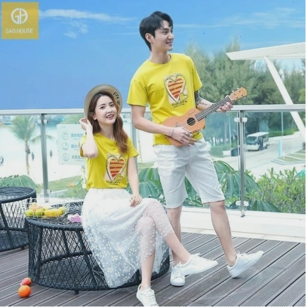 Cặp đôi diện áo hoodie đôi màu xám và quần jean, cùng nhau đi dạo trên bãi biển lúc hoàng hôn