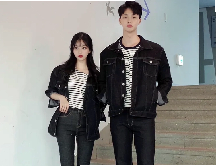 Cặp đôi diện áo khoác bomber và hoodie với tông màu be và nâu, quần jean xanh, tạo dáng nắm tay nhau trên đường phố