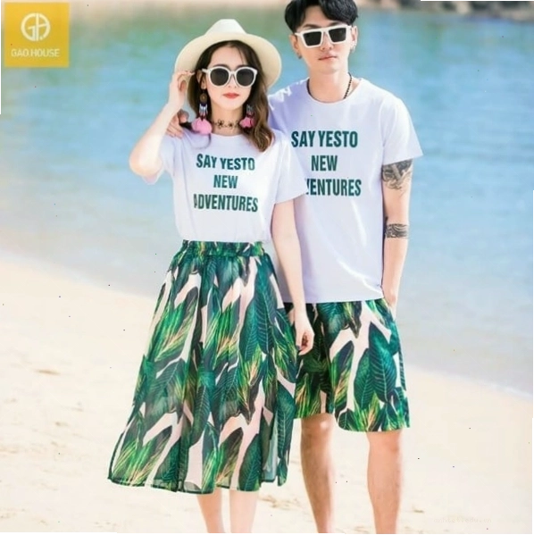 Cặp đôi diện áo thun họa tiết nhiều màu sắc và quần jeans, đứng tạo dáng trước bức tường graffiti