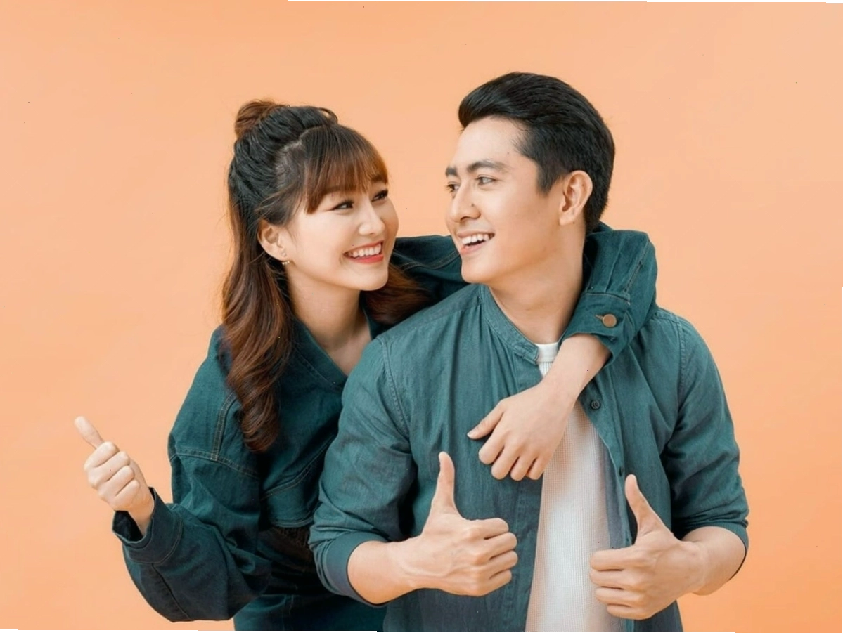 Cặp đôi diện áo thun trắng in chữ và quần jeans năng động, tạo dáng vui vẻ trên đường phố