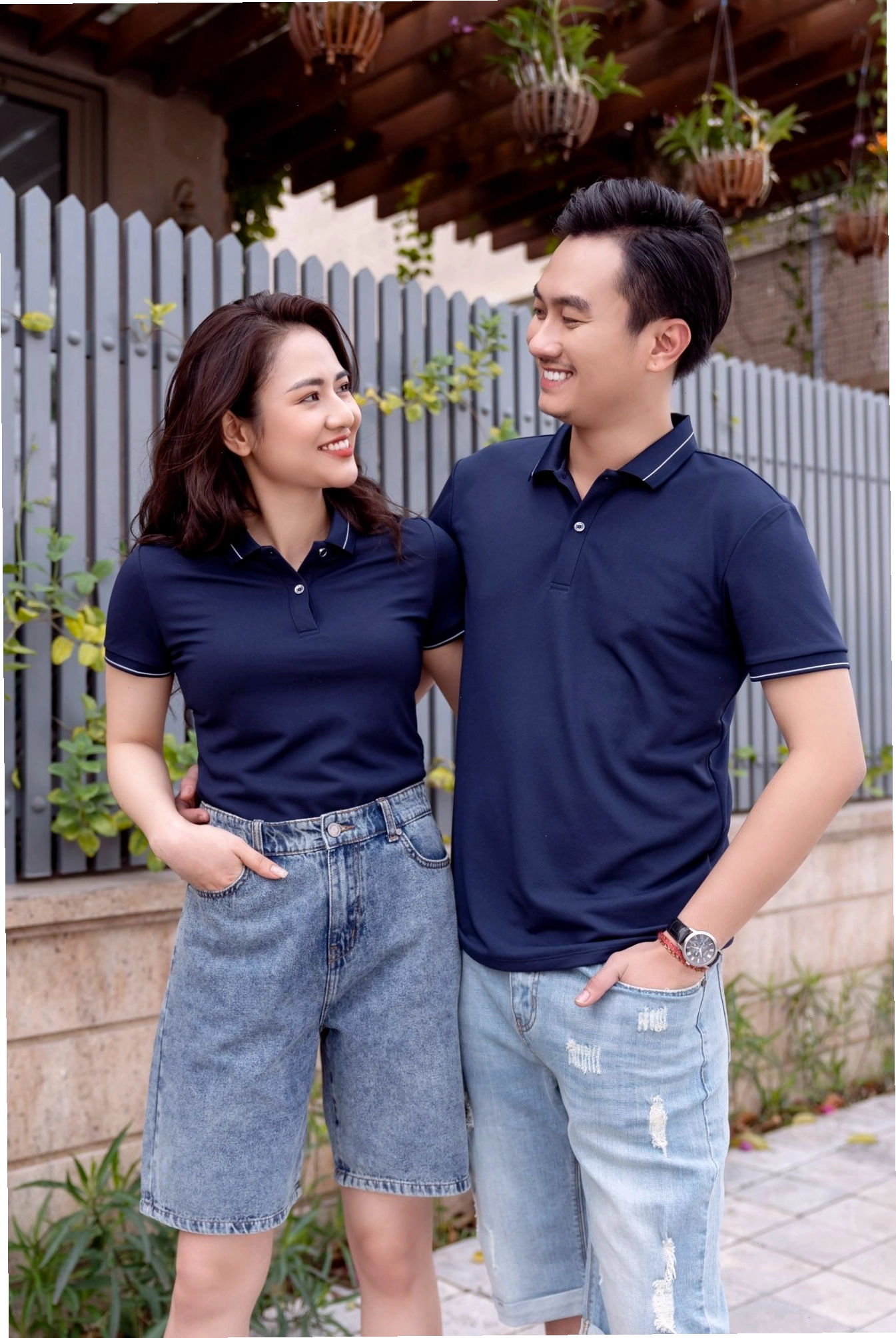 Cặp đôi mặc áo đôi màu cam và trắng, tạo dáng dựa lưng vào nhau