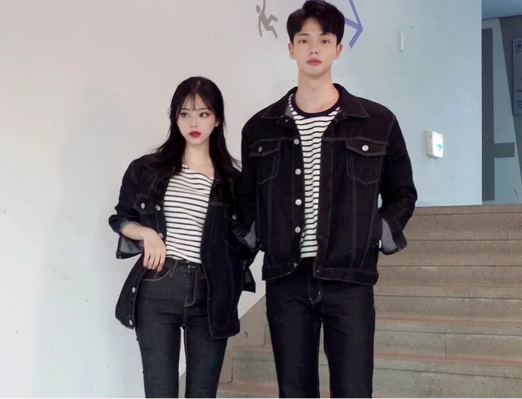 Cặp đôi mặc áo hoodie đôi màu be và quần jeans ống rộng, tạo dáng dựa vào nhau trên phố