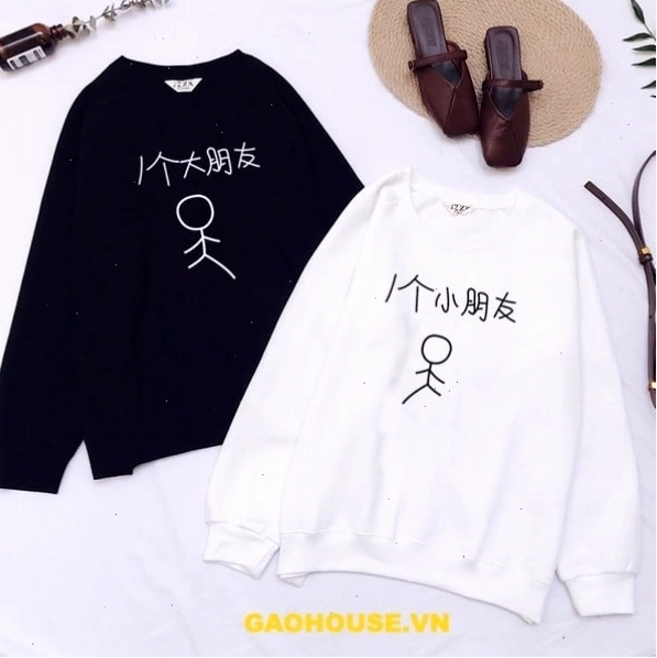 Cặp đôi mặc áo hoodie đôi màu trắng và đen, tạo dáng dựa vào nhau
