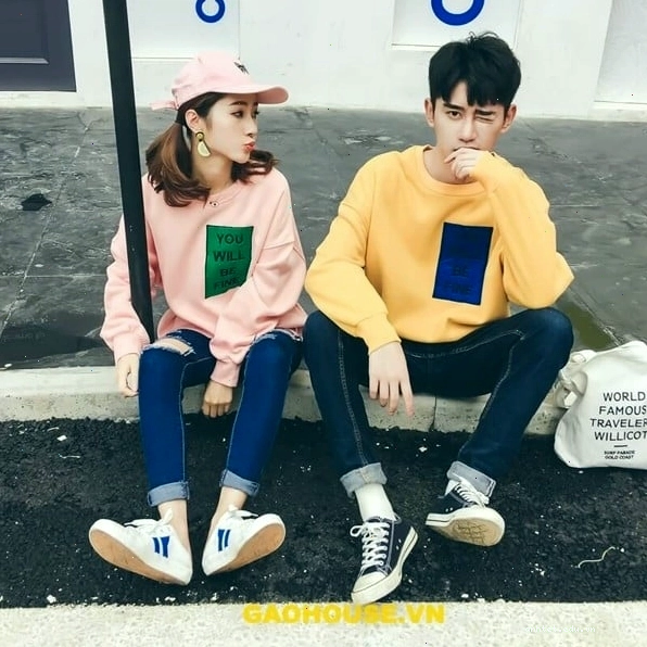 Cặp đôi mặc áo hoodie đôi màu xám khói, tạo dáng đứng cạnh nhau, nhìn vào ống kính