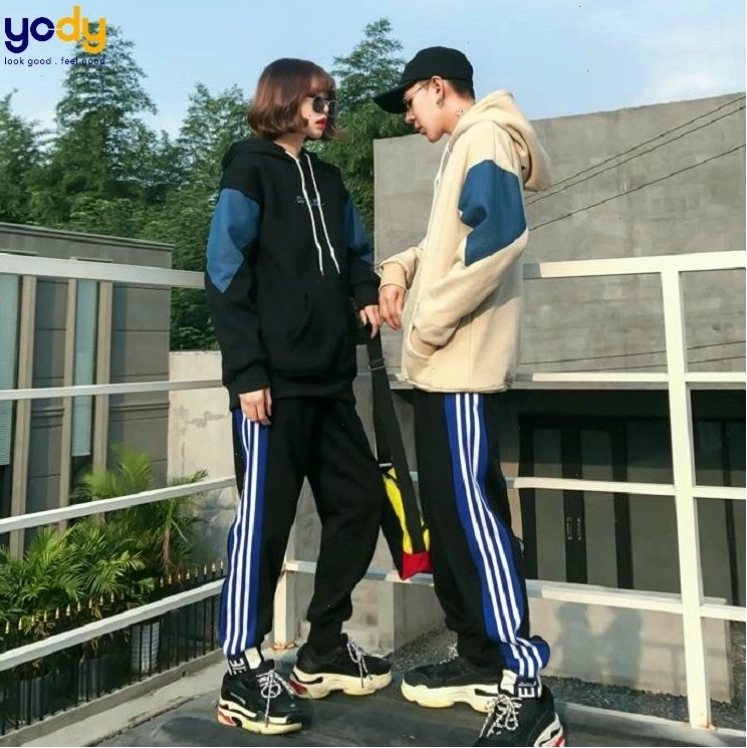 Cặp đôi mặc áo khoác phao đôi màu đen và trắng, quần jean, tạo dáng tay trong tay