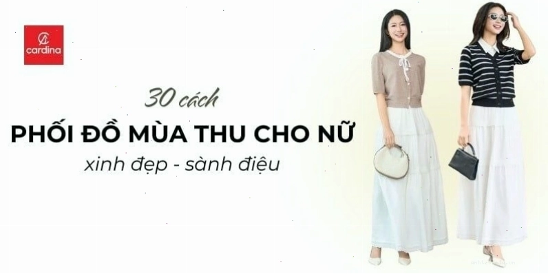 Cặp đôi mặc áo len cổ lọ màu vàng và váy nâu, tay trong tay đi dạo dưới hàng cây lá vàng