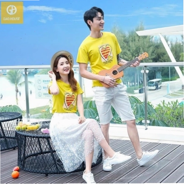 Cặp đôi mặc áo phông trắng có họa tiết đơn giản, tạo dáng nắm tay nhau trên phố