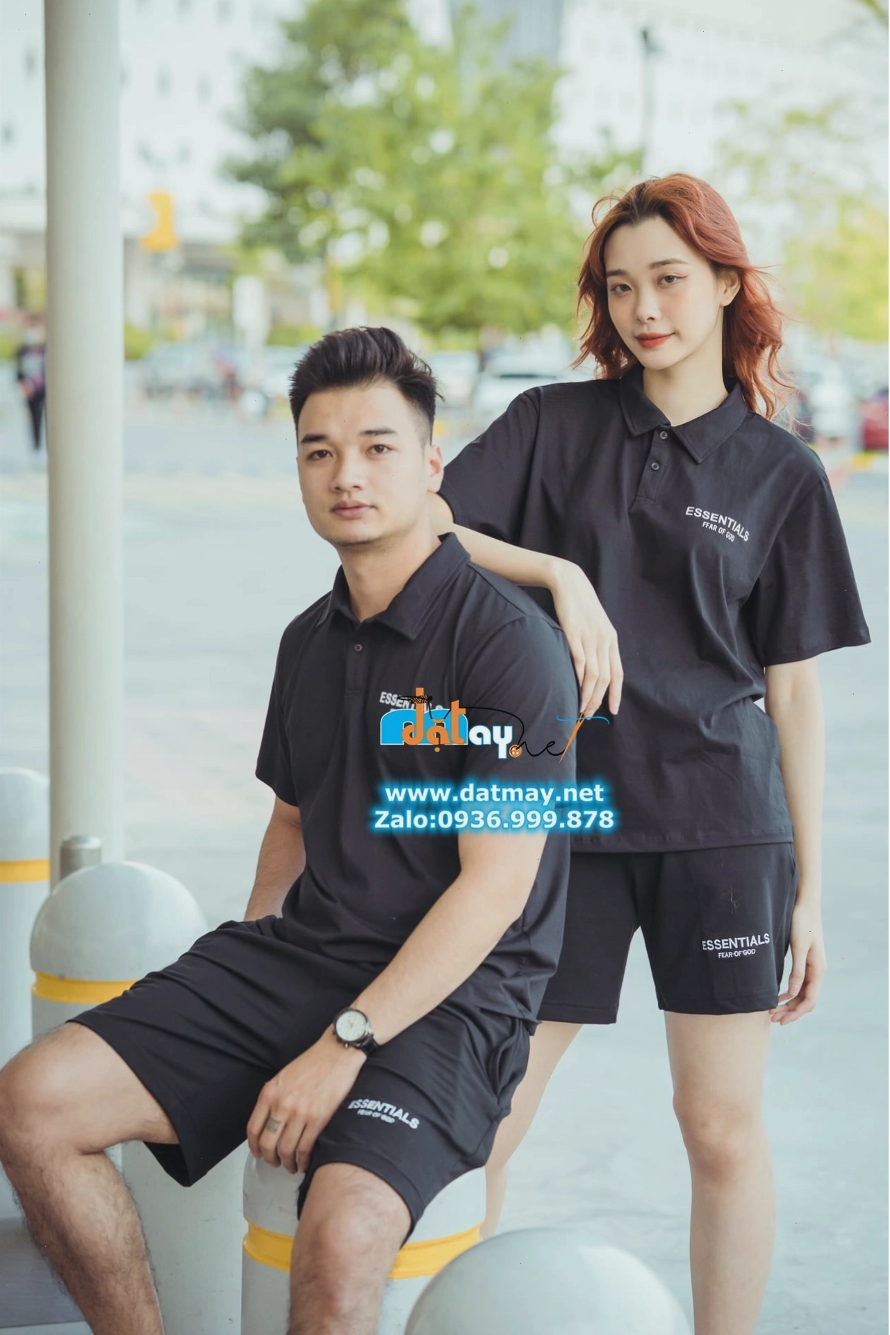 Cặp đôi mặc áo polo đen, tạo dáng nhìn nhau cười tươi