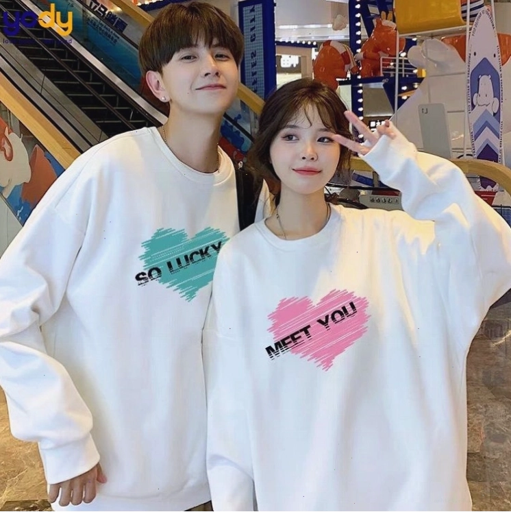 Cặp đôi mặc áo sweater đôi màu vàng và xanh dương, tạo dáng nắm tay nhau