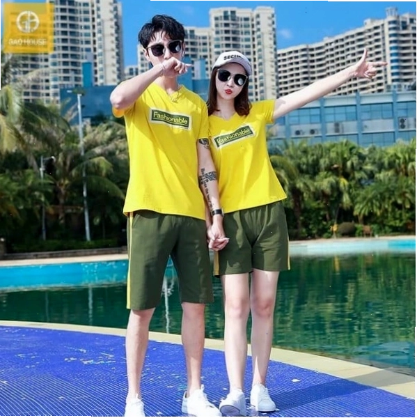 Cặp đôi mặc áo thun đôi có logo nhỏ bên ngực, tạo dáng dựa vào nhau