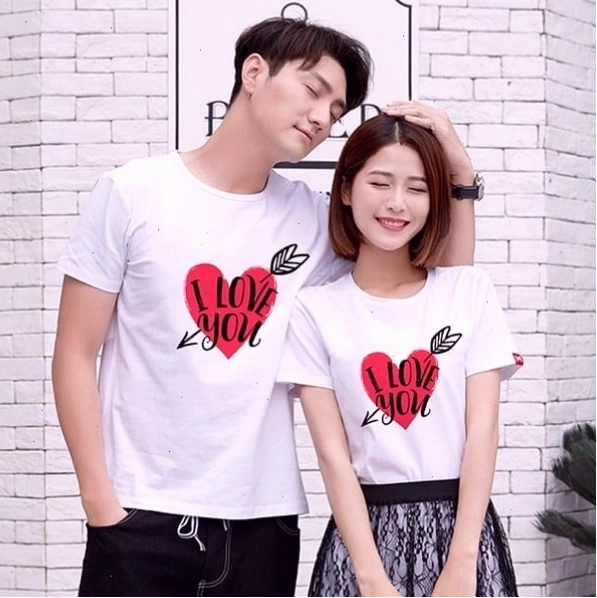 Cặp đôi mặc áo thun đôi trắng, tạo dáng đi bộ trên vỉa hè