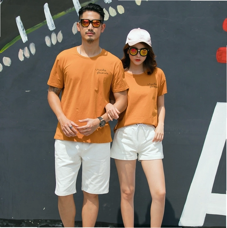 Cặp đôi nắm tay nhau đi dạo trên bãi biển lúc hoàng hôn, mặc đồ đôi đi biển ton-sur-ton