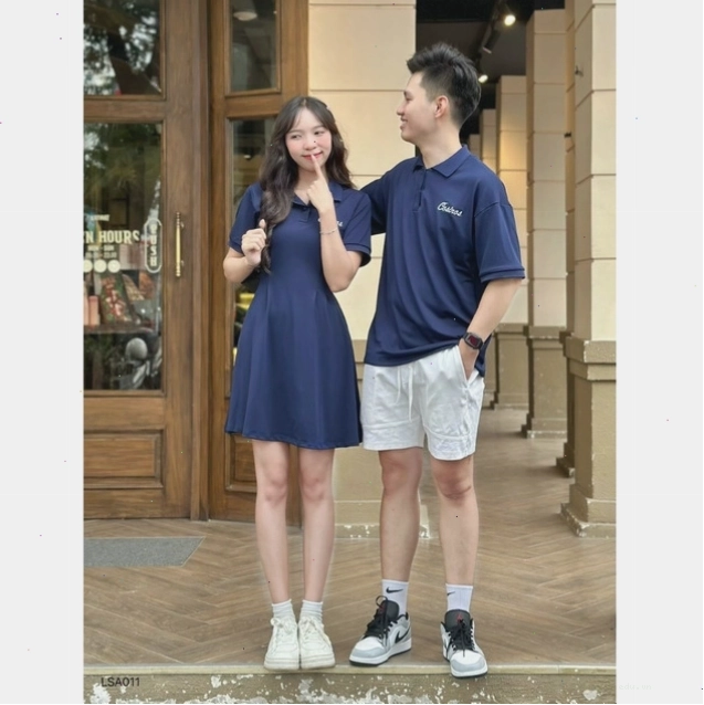 Cặp đôi ngồi tựa vào nhau ngắm hoàng hôn trên bãi biển, mặc đồ đôi đi biển họa tiết hoa