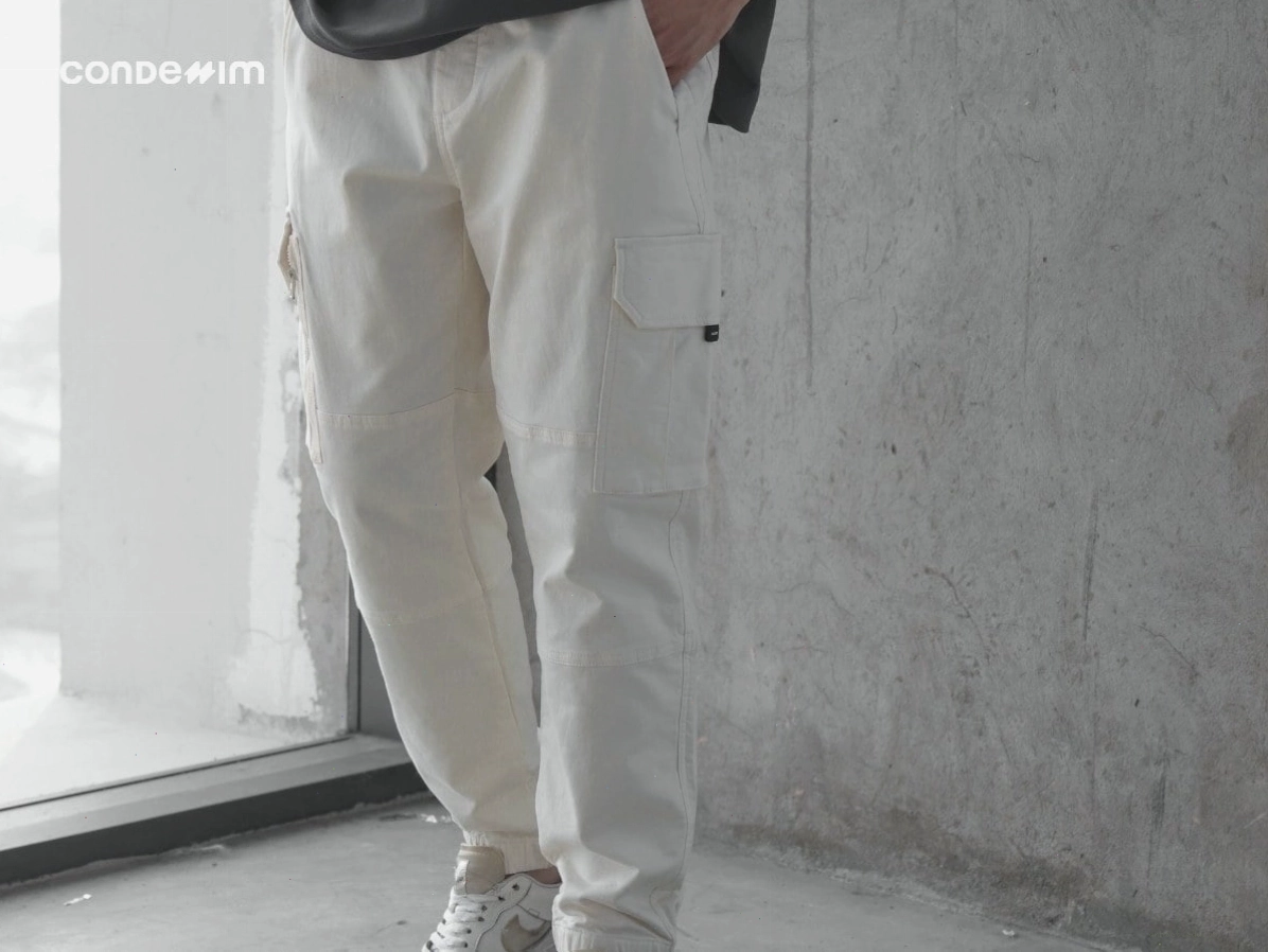 Chàng trai mặc quần kaki ống rộng màu đen, áo thun xám và giày sneaker