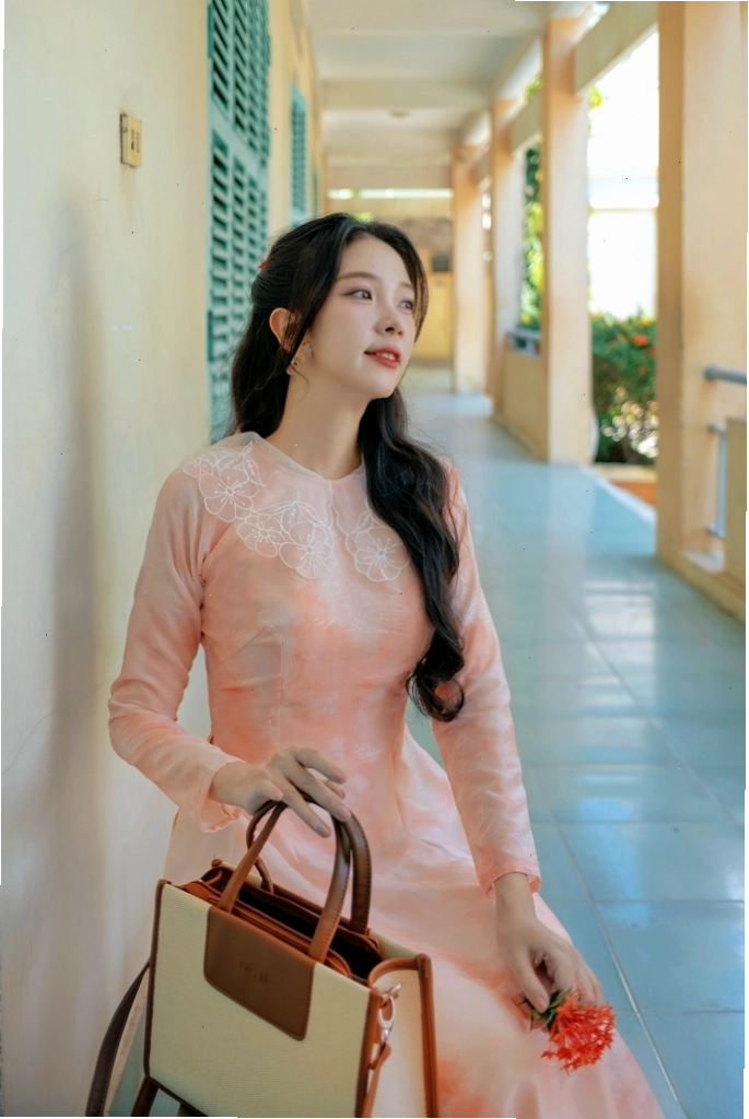 Cô gái diện áo dài cổ lá sen màu cam đất, họa tiết hoa văn chìm, phối cùng quần lụa trắng