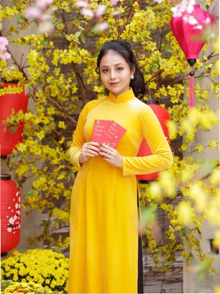 Cô gái diện áo dài Tết truyền thống, tay cầm bao lì xì đỏ, nở nụ cười tươi tắn