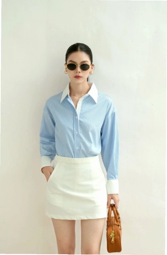 Cô gái diện áo sơ mi oversize phối màu xanh và trắng, quần short vải