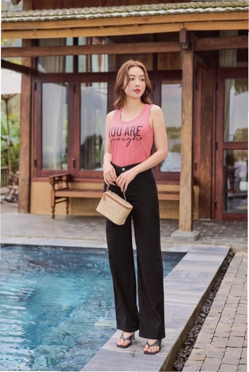 Cô gái diện quần jean ống suông cạp cao, ống rộng, màu xanh bạc với áo hai dây trắng và giày sneaker trắng
