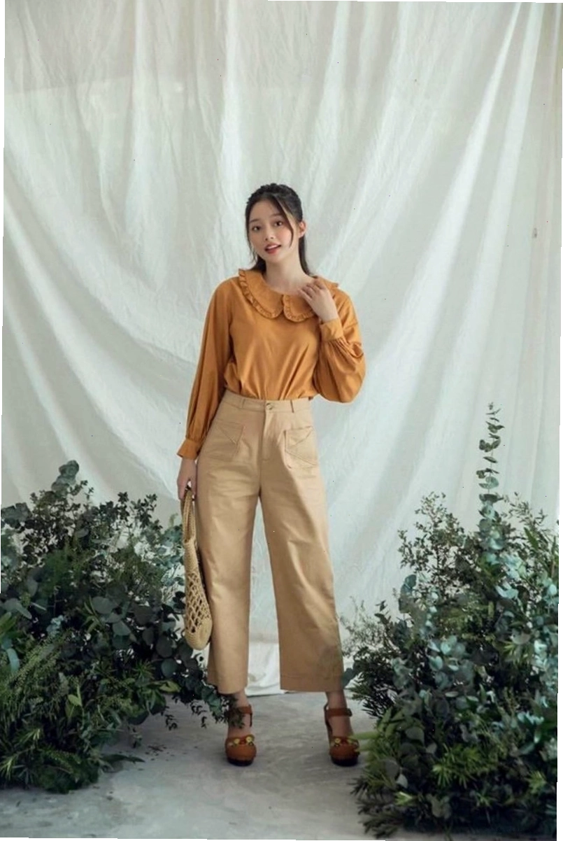 Cô gái diện quần jean ống suông màu trắng với áo croptop kẻ sọc và túi tote