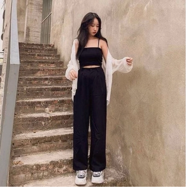 Cô gái mặc áo croptop trắng, quần đũi ống rộng và túi kẹp nách