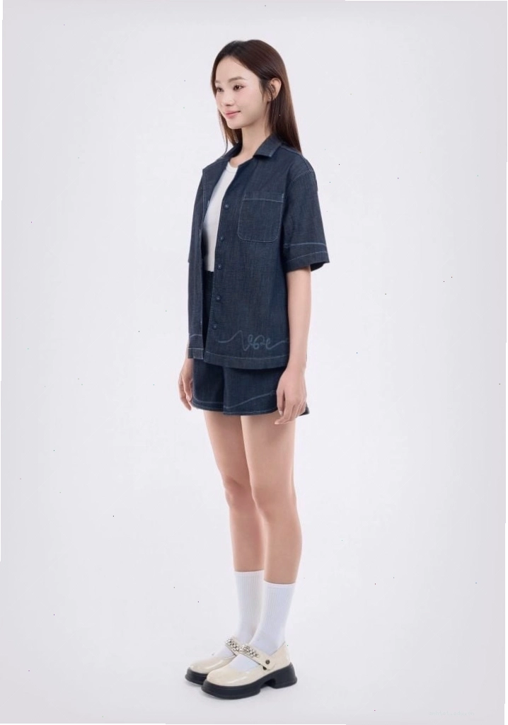 Cô gái mặc áo sơ mi denim nữ dáng rộng, thả cúc ngoài áo hai dây và quần short jeans