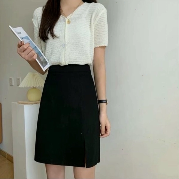 Cô gái mặc chân váy công sở chữ A màu hồng pastel cùng áo sơ mi trắng và túi xách nhỏ