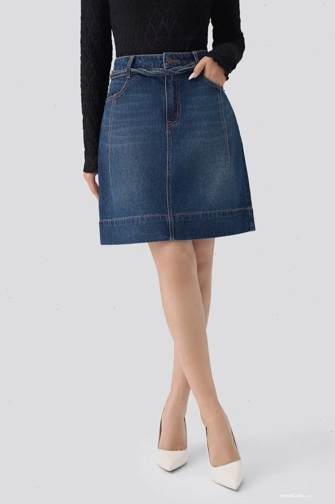 Cô gái mặc chân váy jean chữ A dáng ngắn màu xanh denim phối áo croptop và sneakers