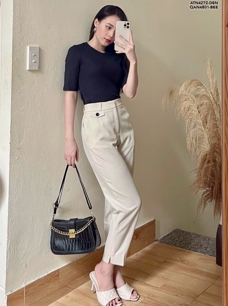 Cô gái mặc quần âu nữ lưng cao ống rộng xẻ tà màu đen phối cùng áo kiểu và giày cao gót