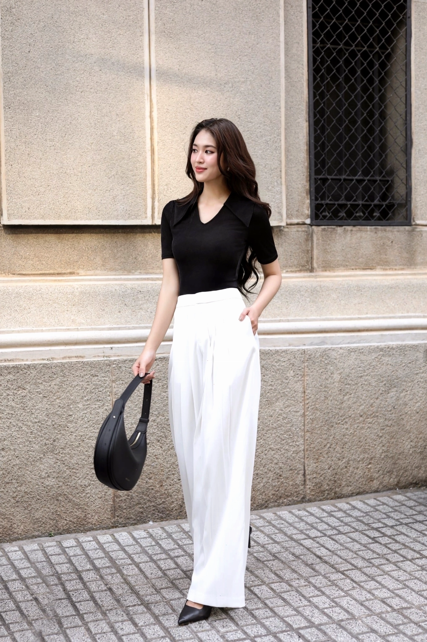 Cô gái mặc quần culottes ống suông màu be, áo thun trắng và giày sneakers