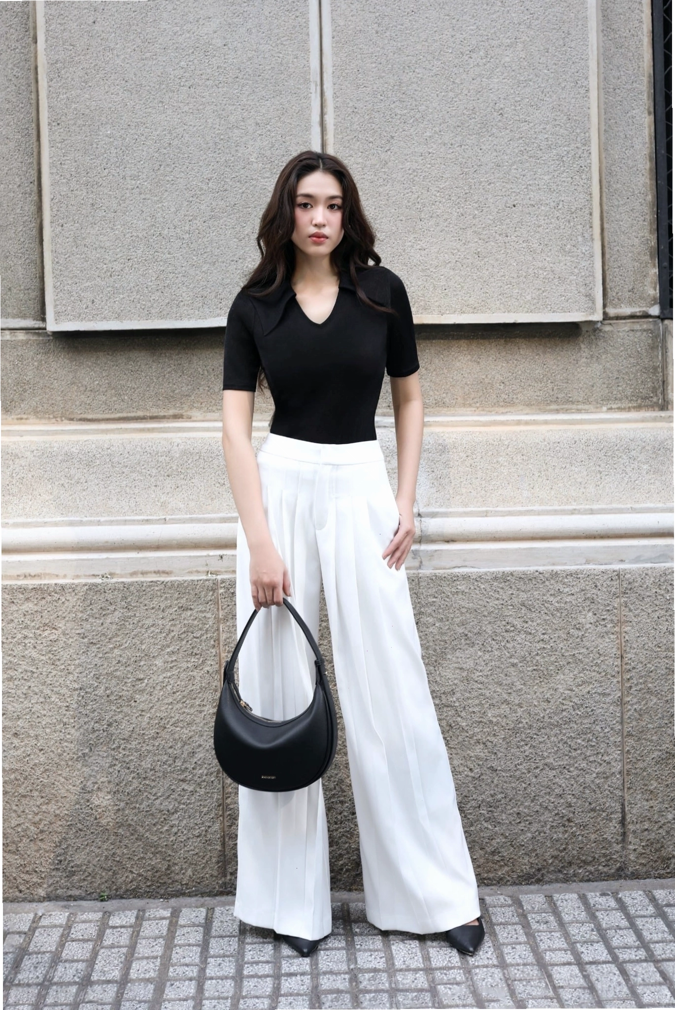 Cô gái mặc quần culottes ống suông xếp ly màu đen, áo ôm tay dài màu xám