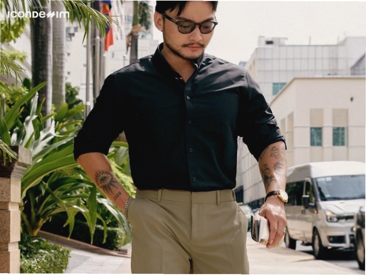 Cô gái mặc quần kaki ống rộng màu nâu, áo hai dây trắng và túi xách mini