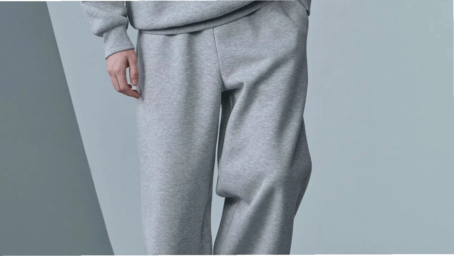 Cô gái mặc quần kaki ống rộng màu xám, áo len cổ lọ màu trắng và giày sneaker trắng