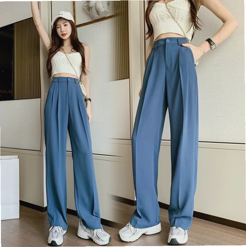 Cô gái mặc quần vải lưng cao màu nâu đất phối cùng áo thun trắng và túi xách kẹp nách