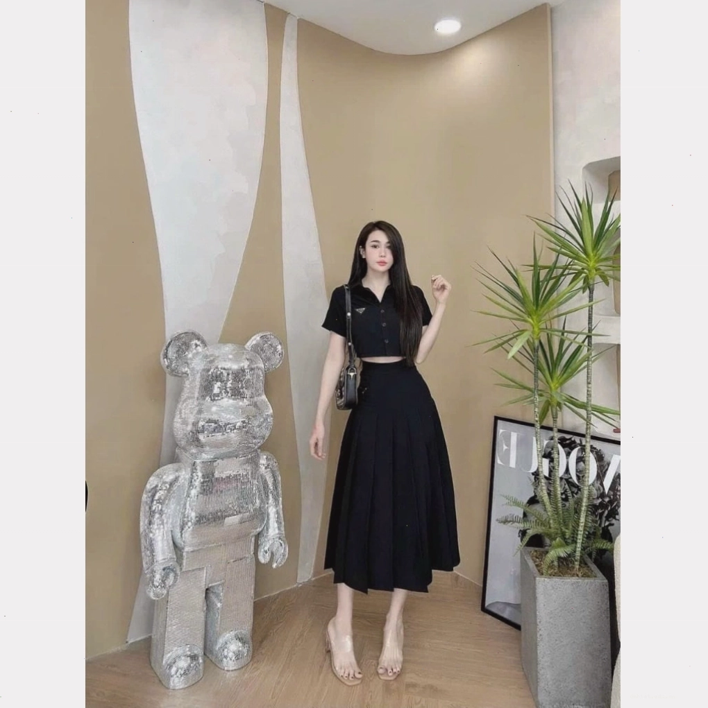 Cô gái mặc set áo croptop đen phối cùng chân váy xếp ly dài màu xám