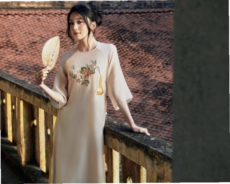 Cô gái tạo dáng năng động với áo dài cách tân màu hồng, tay phồng, phối cùng quần trắng và túi xách nhỏ
