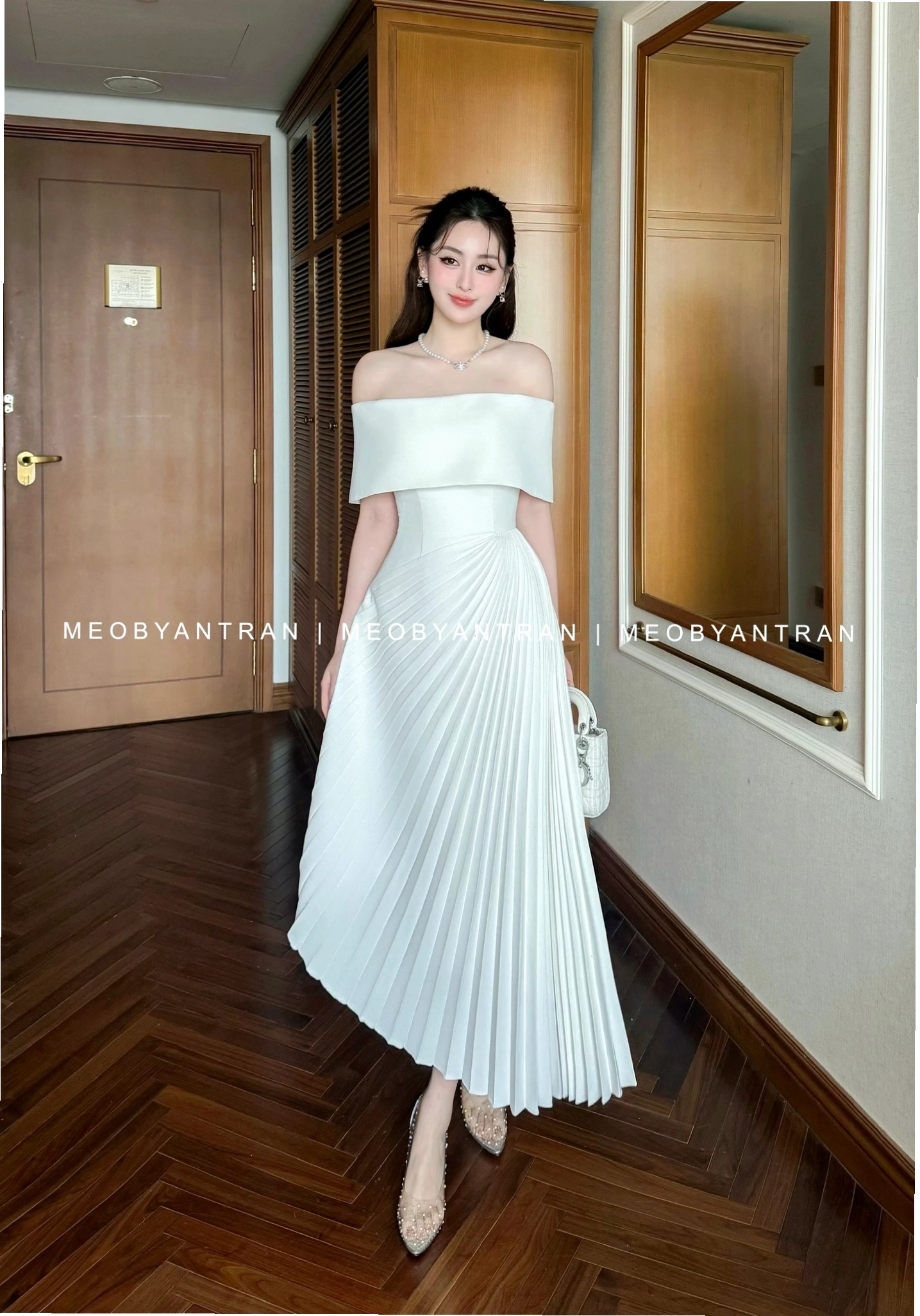 Đầm trắng trễ vai dáng dài, chất liệu lụa cao cấp, điểm nhấn xếp ly tinh tế ở phần eo