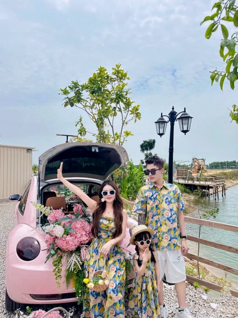 Gia đình mặc đồ đôi đi biển, mẹ và bé gái mặc đầm hoa, bố và bé trai mặc áo sơ mi xanh