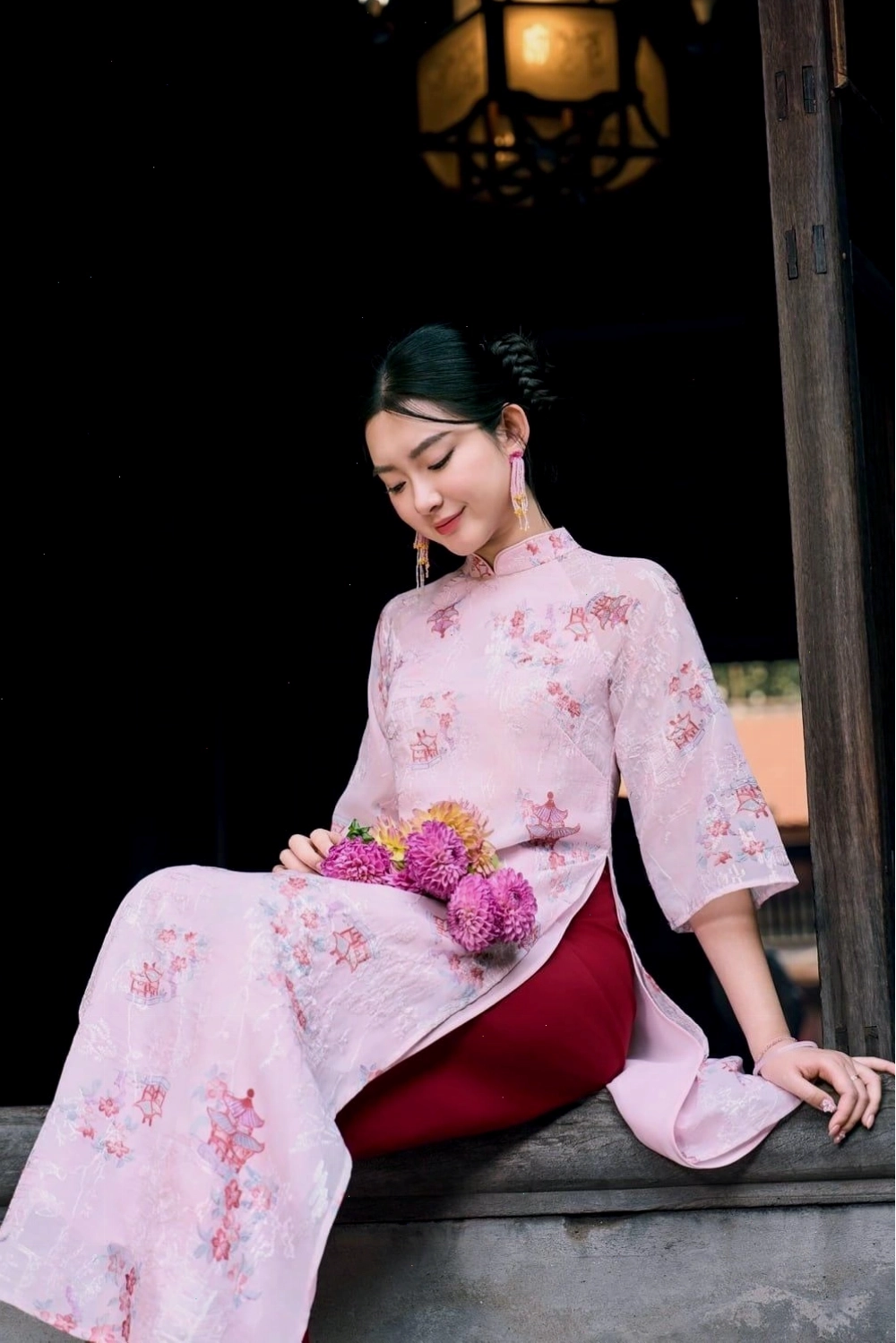 Mẫu áo dài gấm đỏ đô, cổ tròn, tay lỡ, điểm xuyết họa tiết vàng kim sang trọng.